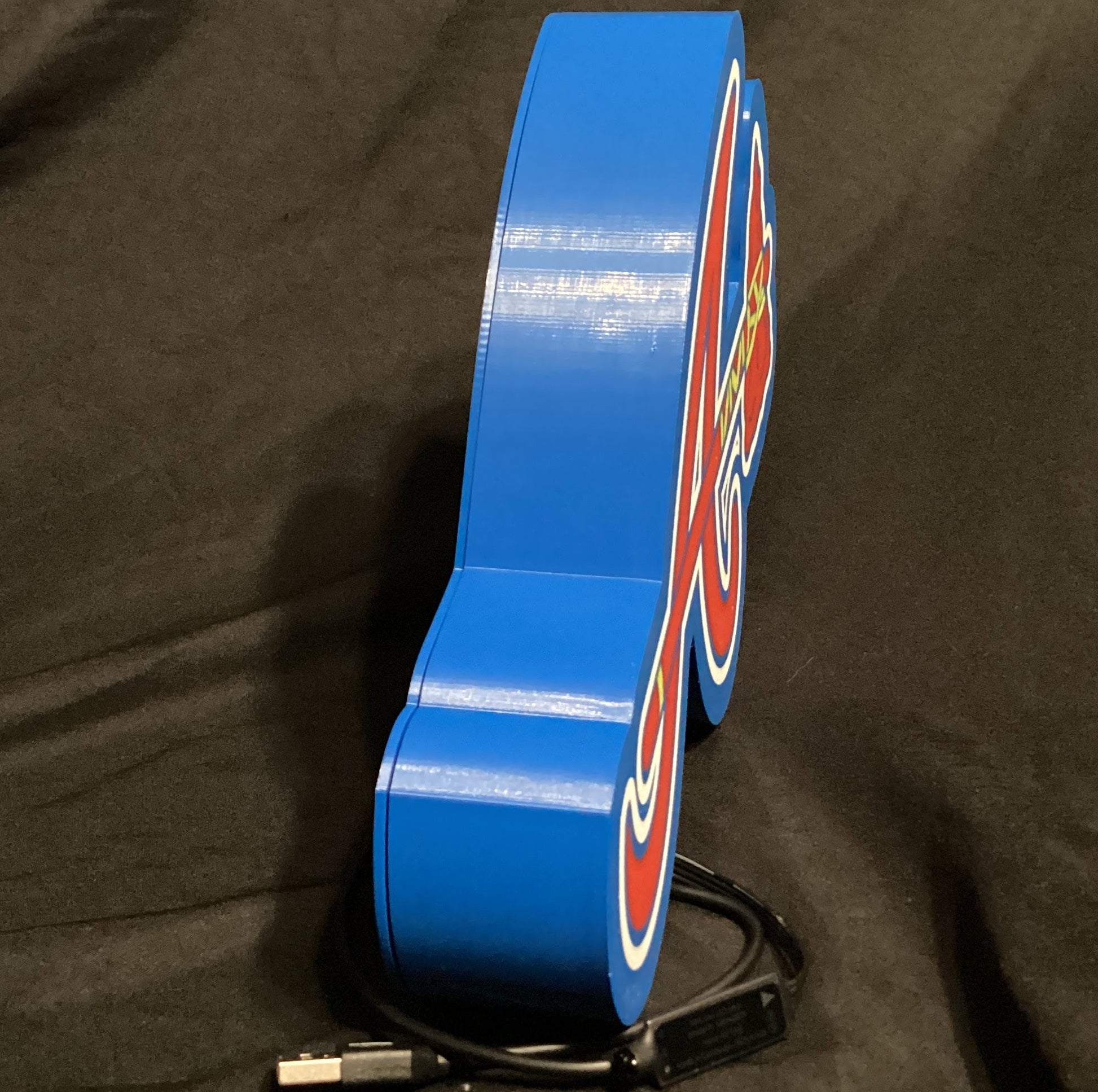 Blue LED sign with a brand logo on a dark fabric background
